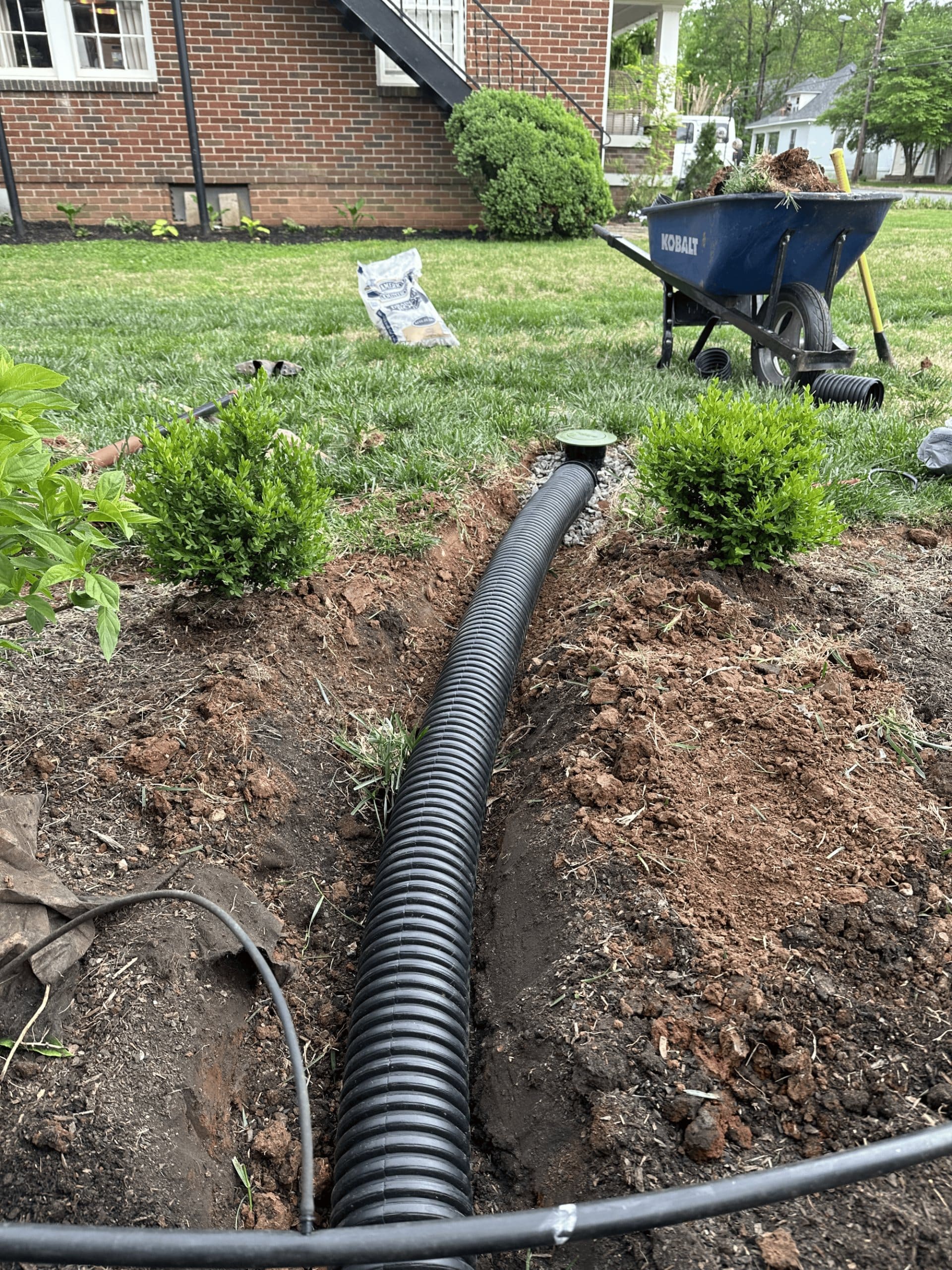 Corrugated drain pipe laid in a trench beside a home