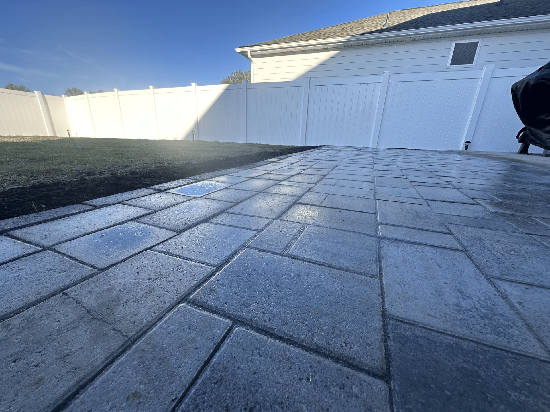Stamped concrete patio beside a white privacy fence
