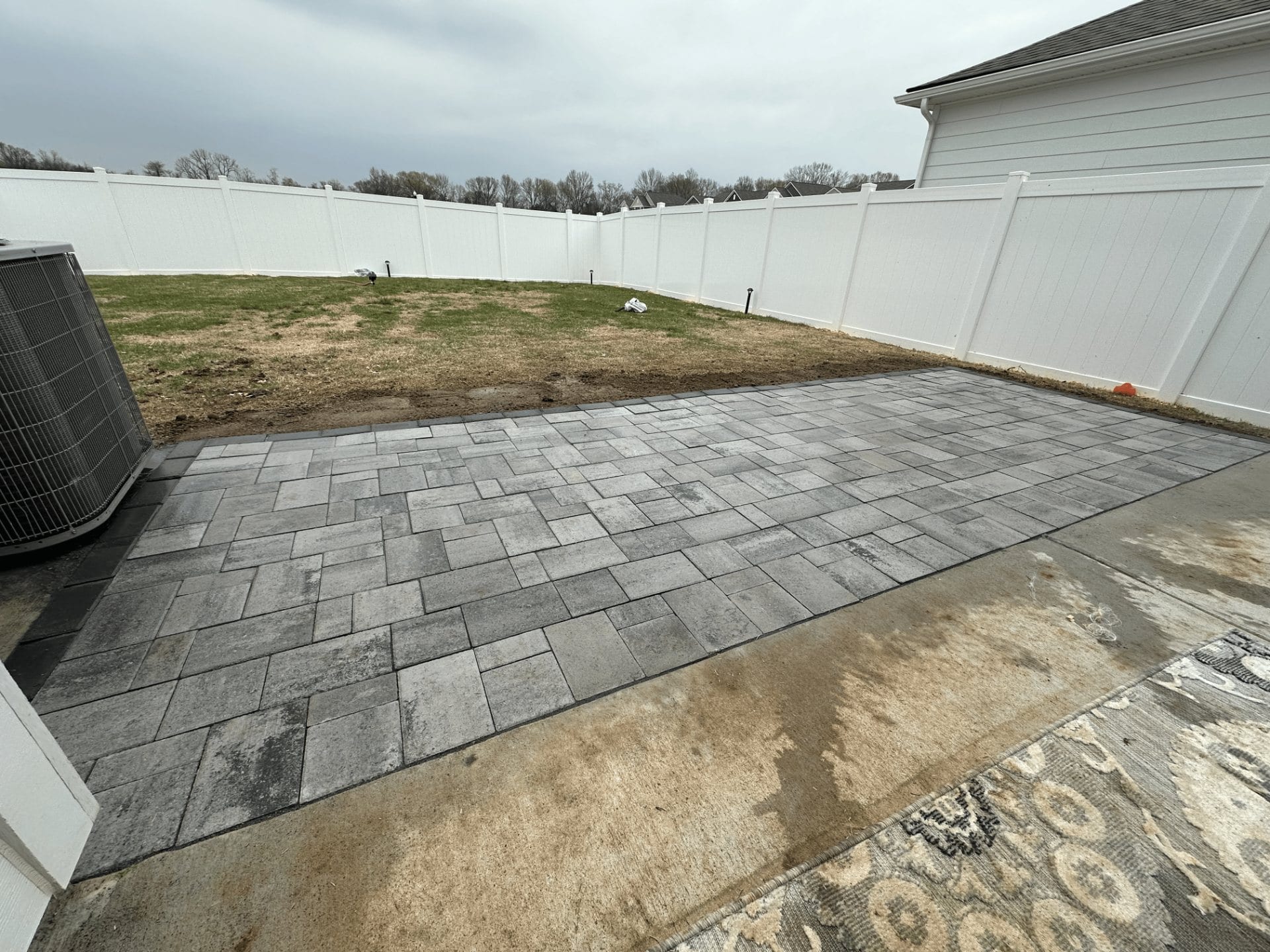 Finished grey paver patio in a fenced backyard