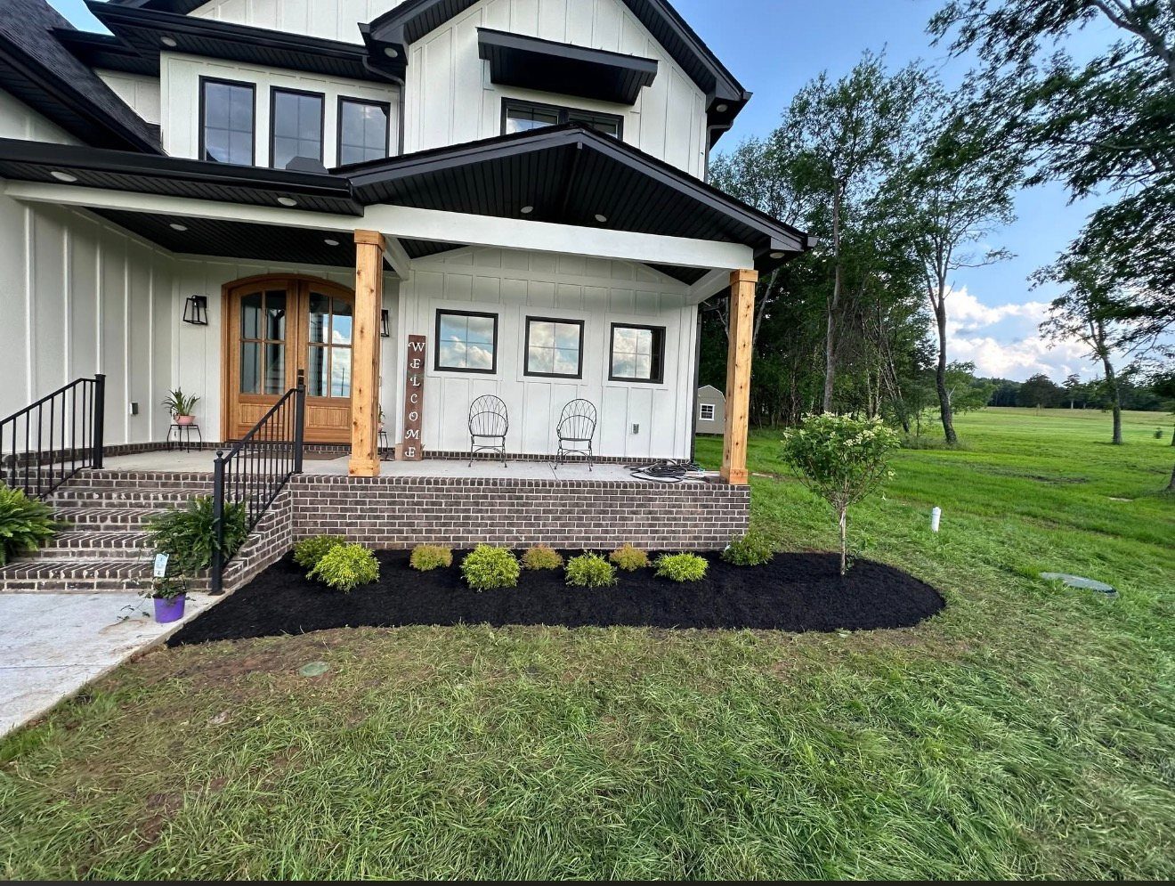 New foundation planting and mulch bed at a farmhouse porch