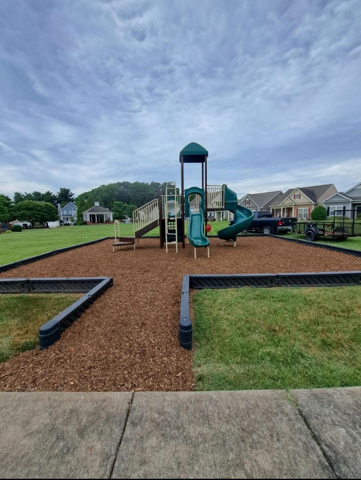 Playground mulch refreshed inside a bordered play area