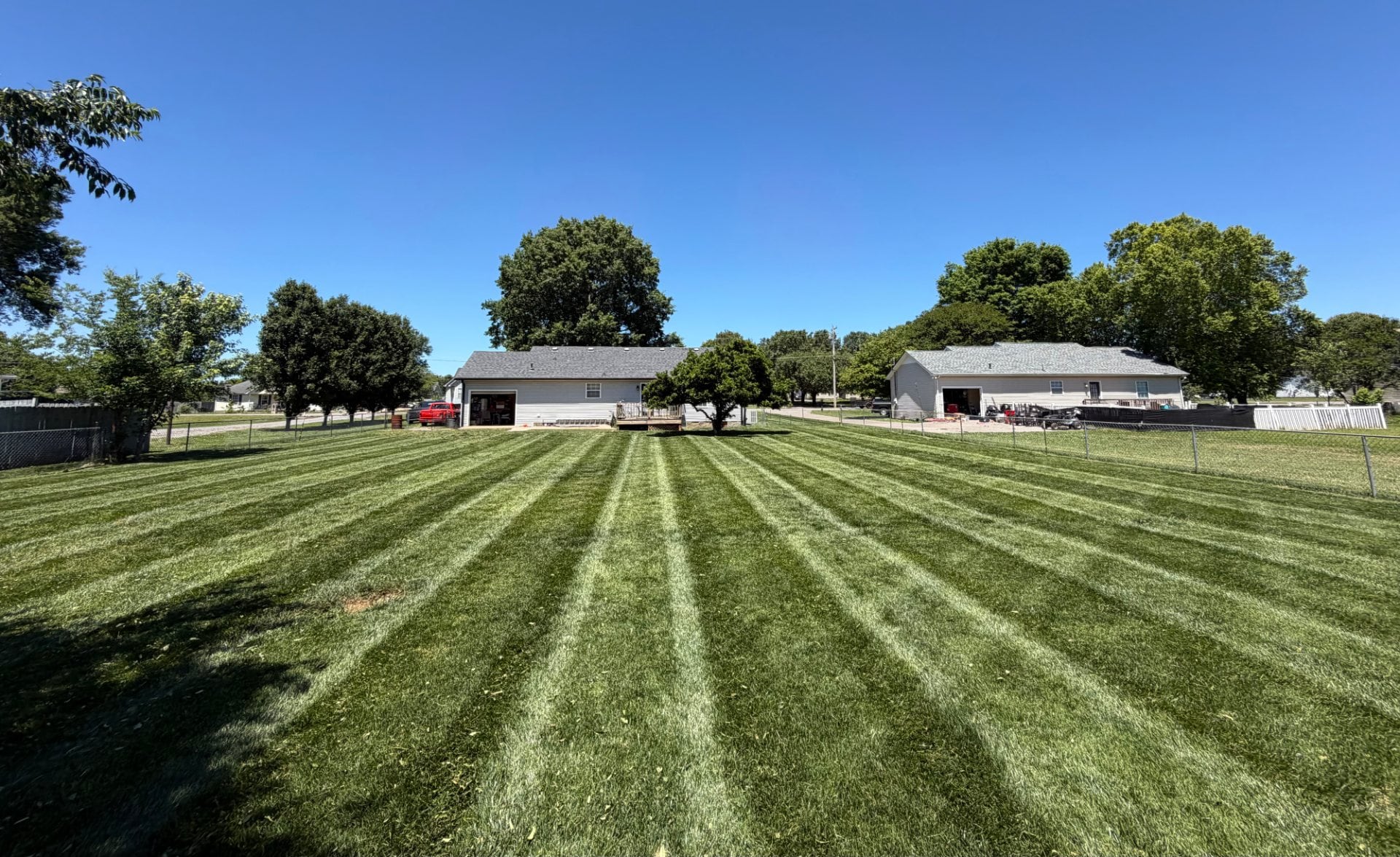 Broad mow stripes across a fenced back lawn