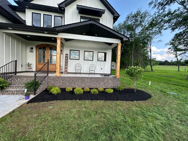 New plantings and mulch beds framing a farmhouse porch